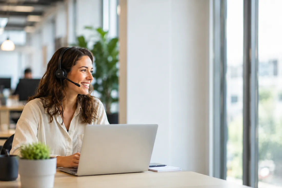 Une conseillère CALL IA, casque-micro sur les oreilles, en conversation téléphonique avec un client professionnel
